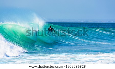 Uluwatu Bali, Indonesia - August 26 2014 : Unknown surfer riding a wave on a  beautiful sunny day. Royalty-Free Stock Photo #1305296929