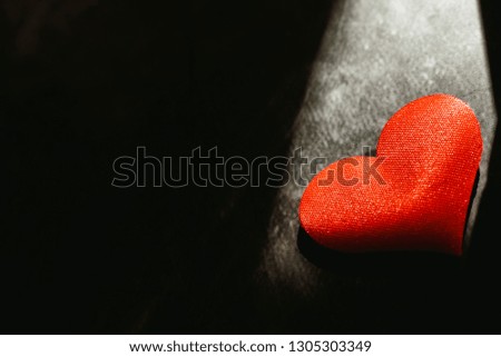 Red hearts isolated dark background illuminated by a ray of sun to use in the background, with a lot of empty space copy space.