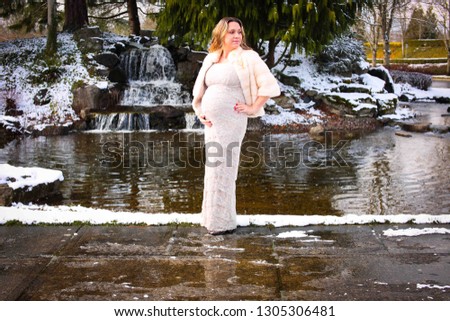 Beautiful Pregnant Woman Posing Outside in a Long White Fancy Dress and in a Beige Fur Jacket, Snow Waterfall in the Background, Portland Oregon, USA, Happy Mother, Pro Life Concept