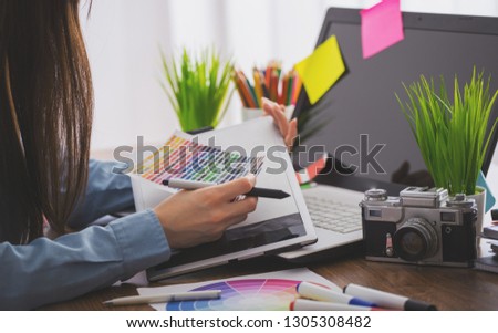 Young cute Graphic designer using graphics tablet to do his work at desk