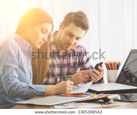 Two young creative designer colleagues using tablet at office