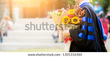 Education theme concept. Graduate holding a hat and flowers. Royalty-Free Stock Photo #1305316360