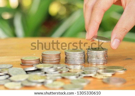 Worker's hand putting money coin stack for growing business with  blurred green garden background.Money, Financial, Business Growth concept.