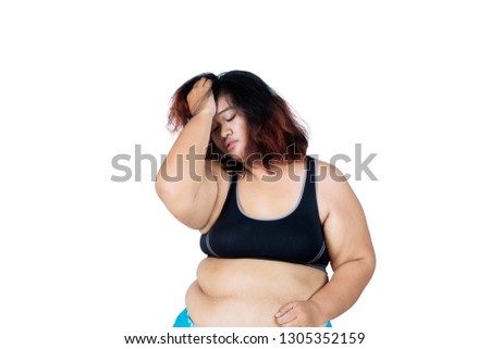 Picture of fat woman looks desperate while wearing sportswear in the studio, isolated white background