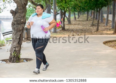 Picture of young fat woman carrying a bottle of water while jogging in the park