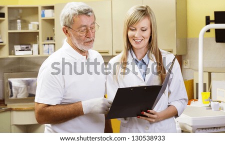 Dentist and his assistant are talking about patient's file
