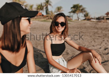 Two european stylish women best friends enjoying summer holidays on sunny beach on background of palms and exotic plants. They are having fun . 