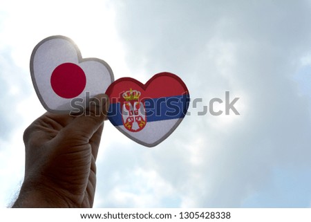 Hand holds a heart Shape Japan and Serbia flag, love between two countries