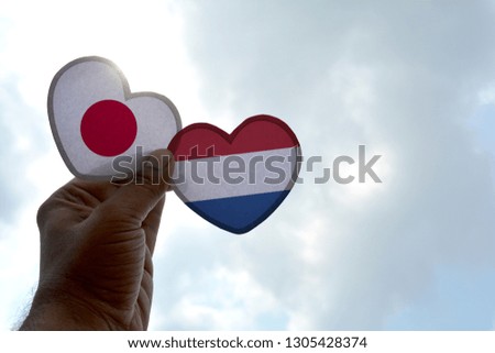 Hand holds a heart Shape Japan and Netherlands flag, love between two countries