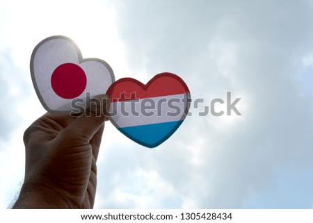 Hand holds a heart Shape Japan and Luxembourg flag, love between two countries