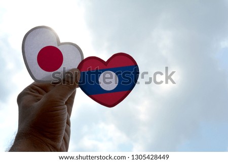Hand holds a heart Shape Japan and Laos flag, love between two countries