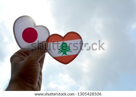 Hand holds a heart Shape Japan and Lebanon flag, love between two countries