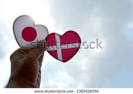 Hand holds a heart Shape Japan and Denmark flag, love between two countries