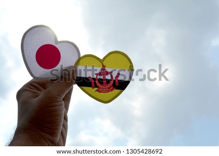 Hand holds a heart Shape Japan and Brunei flag, love between two countries