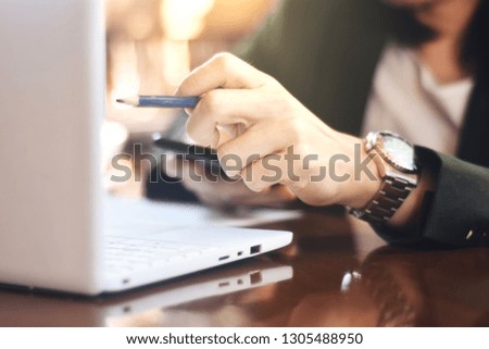 The picture of officer working action on wooden table, consist of laptop, paper and pencil. Selective focus