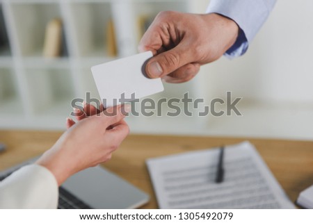 cropped view of businessman giving empty business card to female colleague 