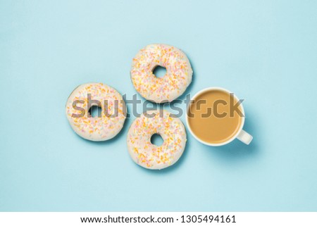White Cup, coffee or tea with milk and fresh tasty donuts on a blue background. Bakery concept, fresh pastries, delicious breakfast, fast food. Flat lay, top view.