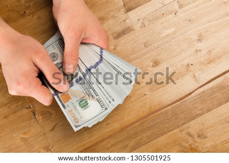 Man count the new us dollars on wooden table 