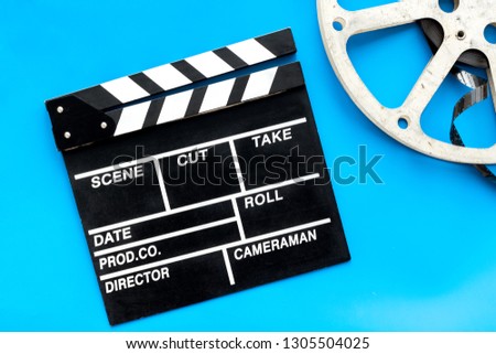 Filmings concept. Clapperboard and film stock on blue background top view copy space