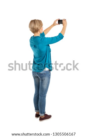 Back view of standing young beautiful woman and using a mobile phone isolated on white background