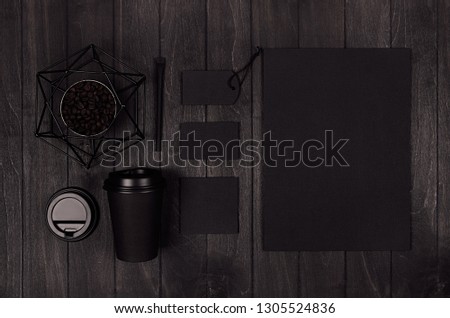 Modern elegance workplace or concept design for restaurant and coffee shop advertising - black paper cup, cap, blank paper, stationery, six-pointed star on dark wood board.