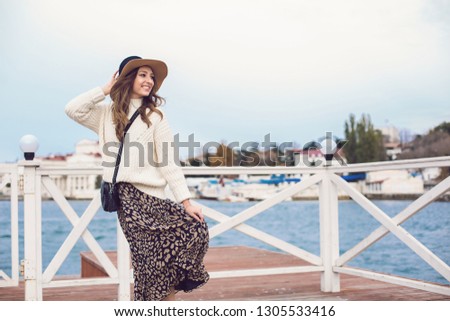Lifestyle fashion portrait of young stylish woman walking on the street, near the sea
