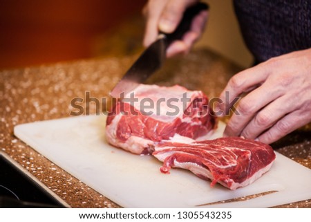 man cuts fresh meat for steak on a cutting board