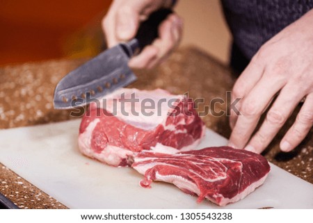 man cuts fresh meat for steak on a cutting board