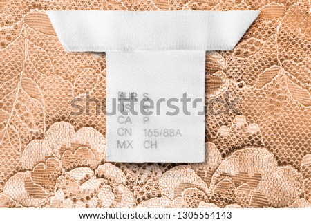 S size clothes label on yellow lacy background closeup