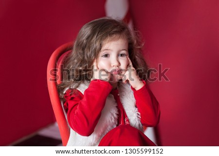 New Year 2020! Christmas, holidays and childhood concept. Merry Christmas and happy holidays! Close-up portrait. Little curly girl on an isolated red background. Bright emotions of child. Birthday