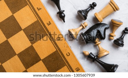 Chess set and chessboard  lie on a light gray table.