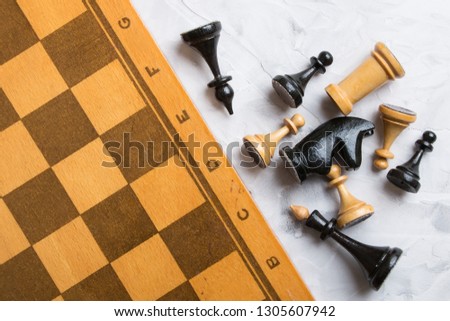Chess set and chessboard  lie on a light gray table.