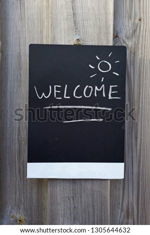 Welcome written on a chalkboard hanging in the garden                     