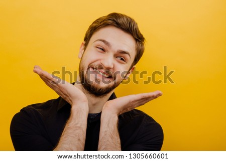 funny man smiles with hands near face, facial expression positive, on yellow background, isolated