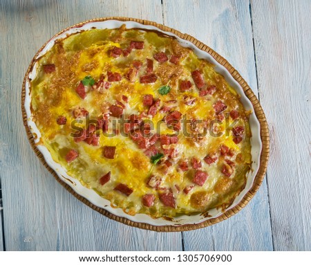 Twice Baked Potato Casserole, Smash the potatoes with a potato masher. Add the cheese, seasoned salt,Cheddar , sour cream, milk, butter, Royalty-Free Stock Photo #1305706900
