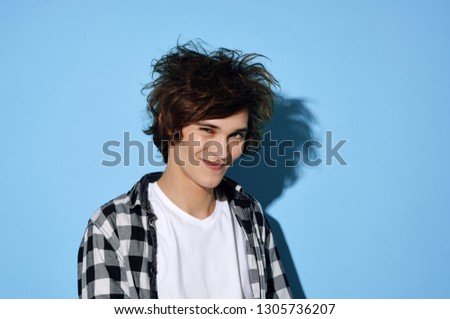 Cheerful nice guy with disheveled hair on a blue isolated background