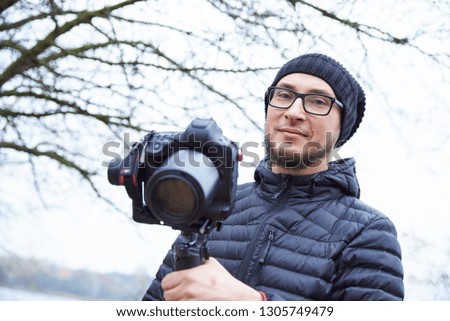 male photographer in a cap shoots a video camera on a cold outside photo.