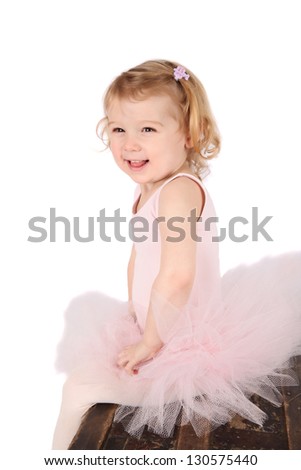 Little ballet girl wearing a pink tutu on an antique trunk
