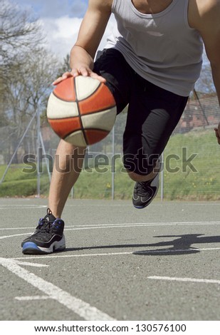Portrait of Basketball Player dribbling the ball in Motion Royalty-Free Stock Photo #130576100
