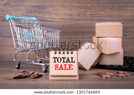 Total Sale concept. Paper boxes, shopping cart and computer keyboard on wooden background. Selling goods or services online over the internet