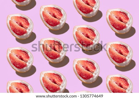 red pomelo on texture background of fashion trendy pastel pink color paper in minimal concept. minimal pattern