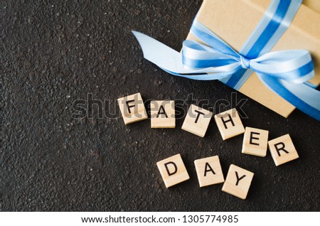 Happy Father's day greeting card with decorated gift box on dark background.