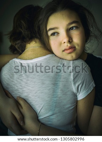 Pensive teen girl put her head on mother's shoulder