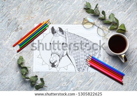 Adult anti stress coloring picture, pencils and cup of coffee on table, top view