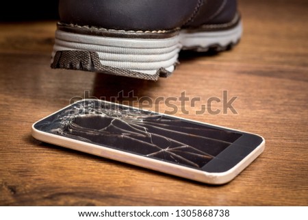 The man stepped on a cell phone and damaged the glass. A broken mobile phone needs to be repaired