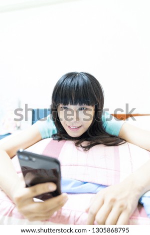 An Asian girl uses a smart phone in bed. Use mobile video, self-timer.