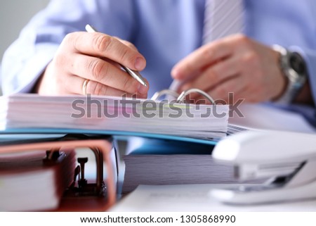Clerk arm fill and sign important form with silver pen binded to pile of hard cover case folder closeup. Make note gesture read sale agent bank job loan credit mortgage investment legal law concept