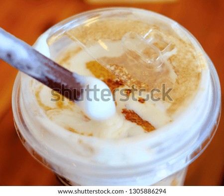 Close up Taiwan iced milk tea with black pearl bubble serve in takeaway plastic glass topped with milk foam and melted brown sugar on wooden table.