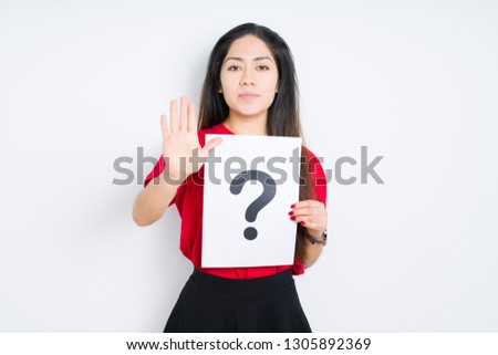 Young brunette woman holding paper with question mark over isolated background with open hand doing stop sign with serious and confident expression, defense gesture