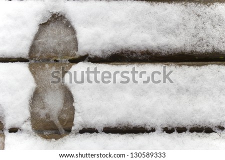 The footprint of a person in the white snow fallen on a wooden floor.